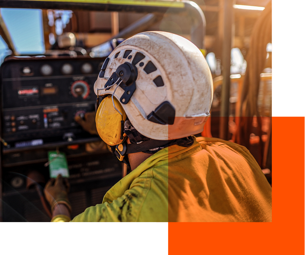 Construction worker from behind with hard hat and ear protection.