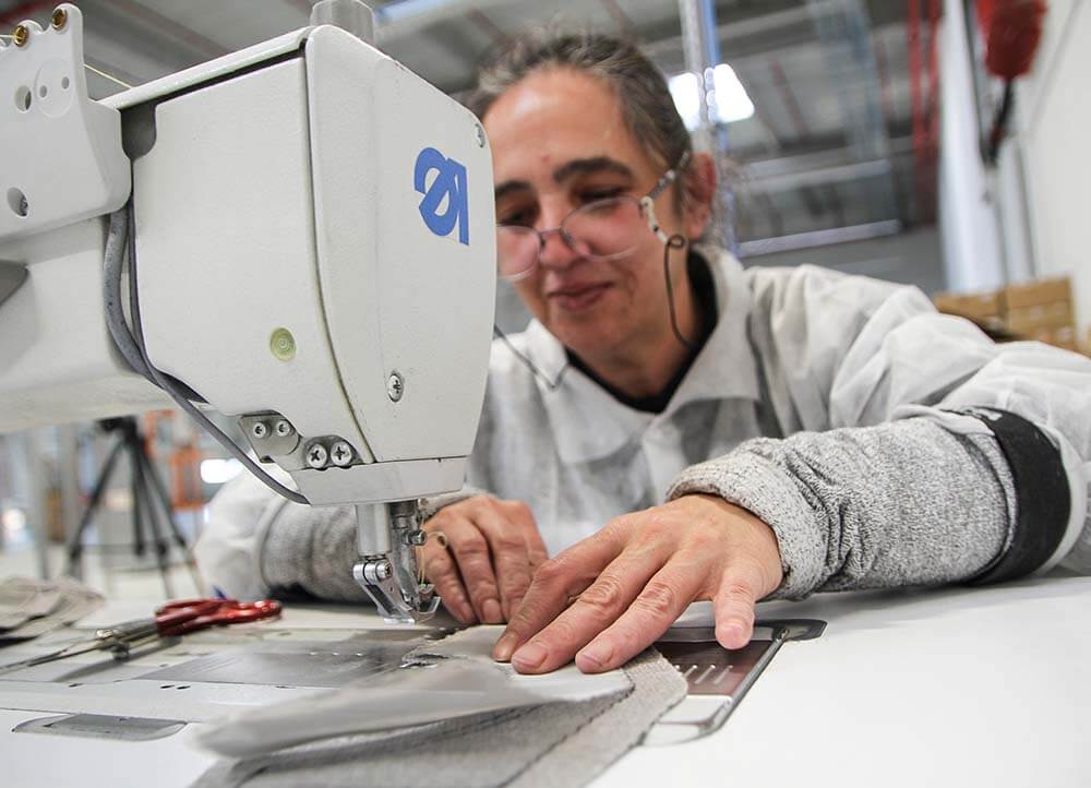 Employee sews textiles for tmax insulation